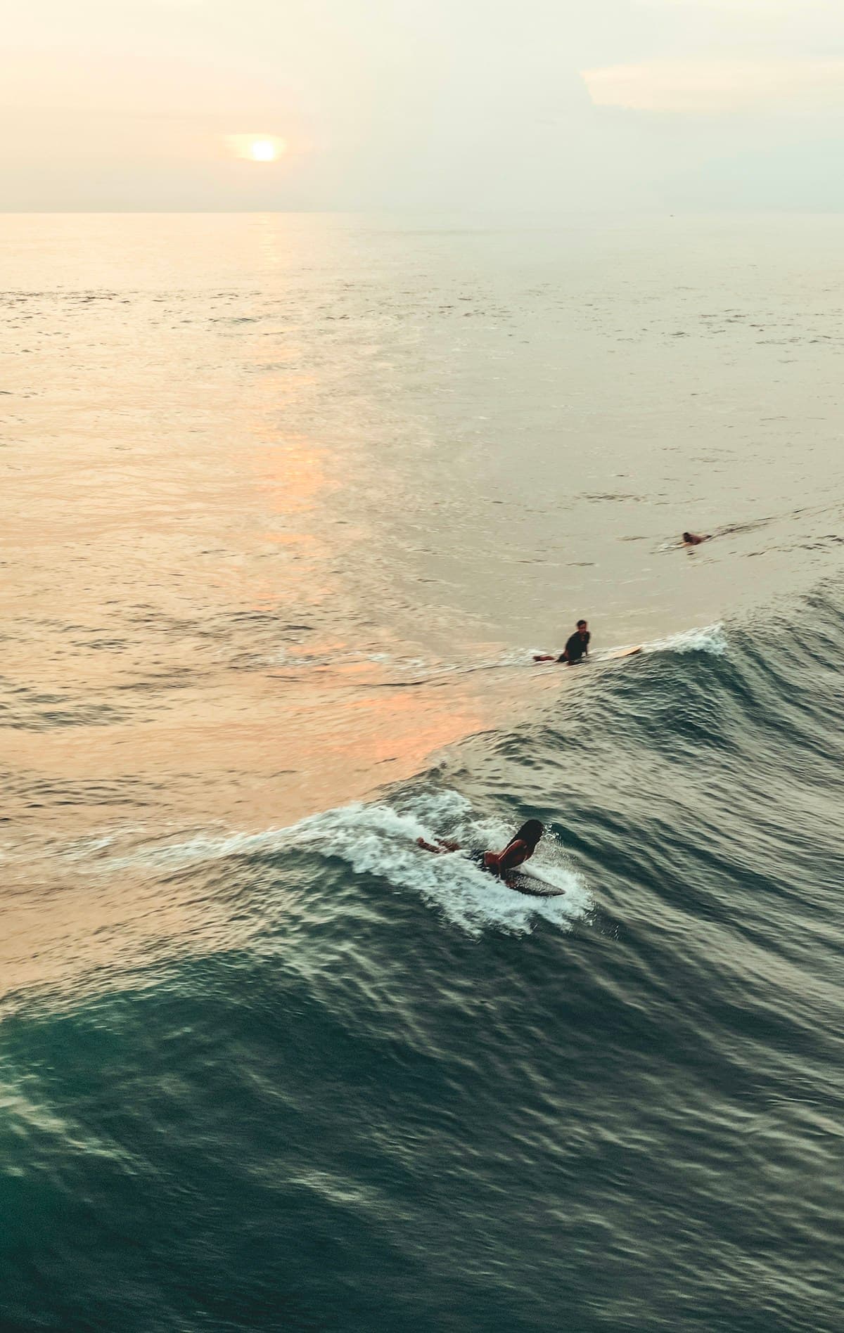 Des surfeurs glissent sur une vague à Canggu dans la lumière du soir