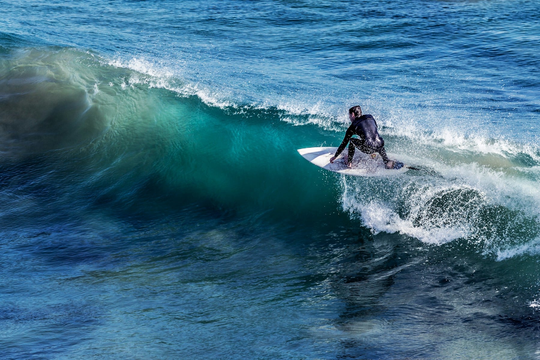 Un surfeur suit la face d’une vague atlantique aux reflets turquoise
